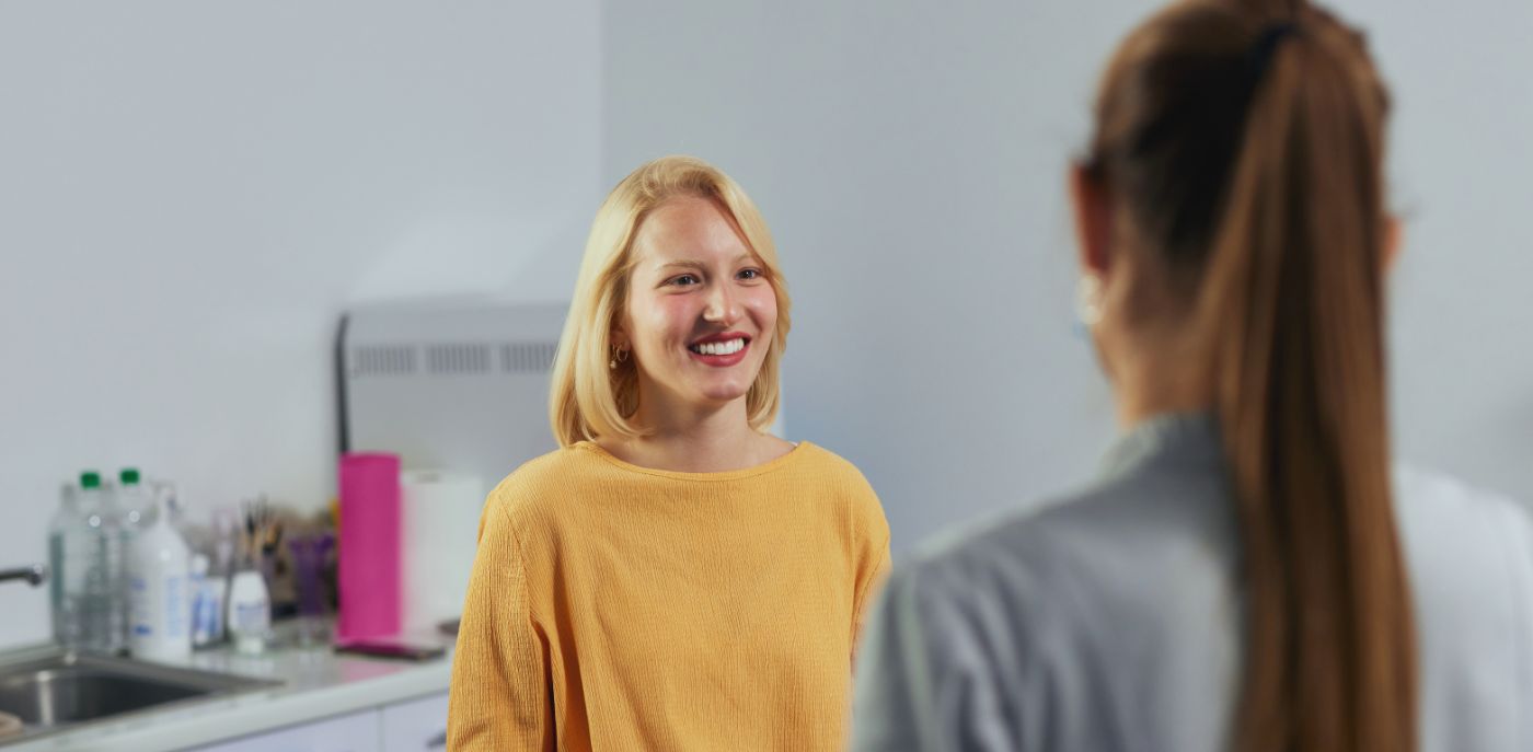 Blonde woman smiling at dental team member